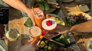 people toasting with drinks, salads and meat on the table